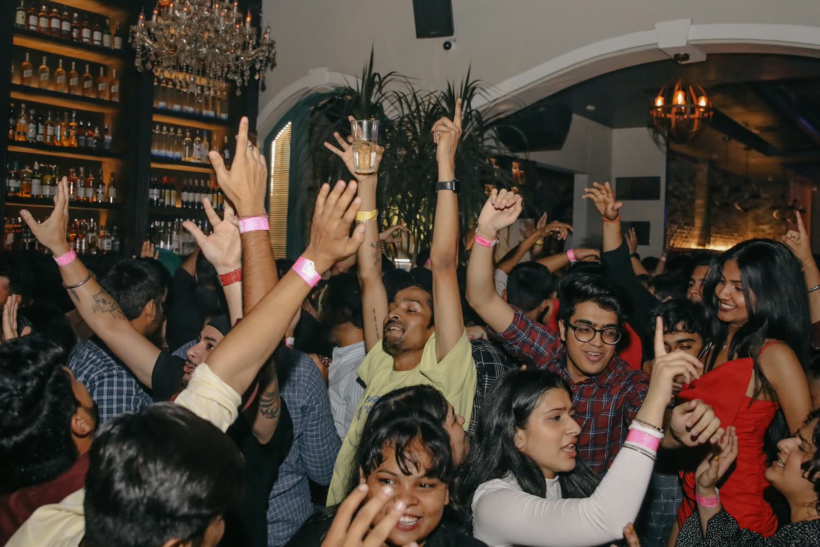 Un grupo de amigos bailando con los brazos en alto durante una fiesta de noche