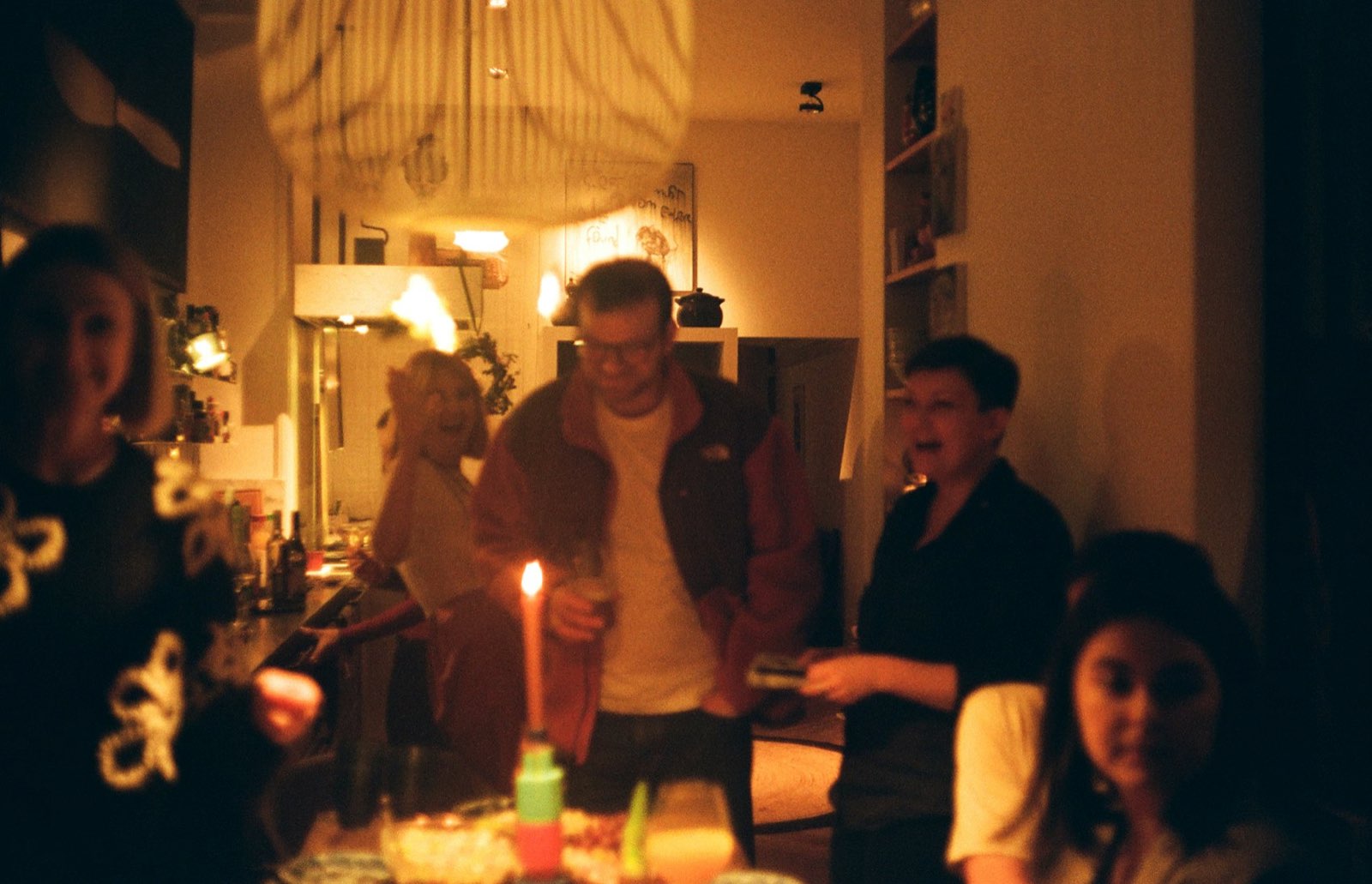 Amigos celebrando un cumpleaños en casa a la luz de una vela
