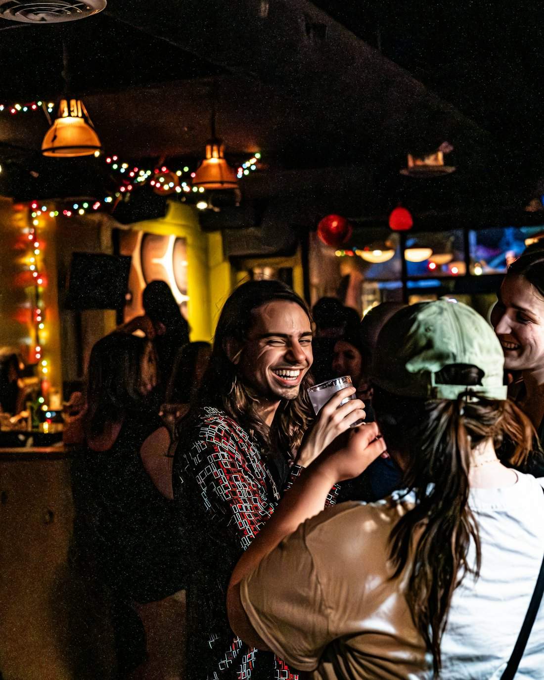 Amigos riendo en un bar pequeño con luces de colores