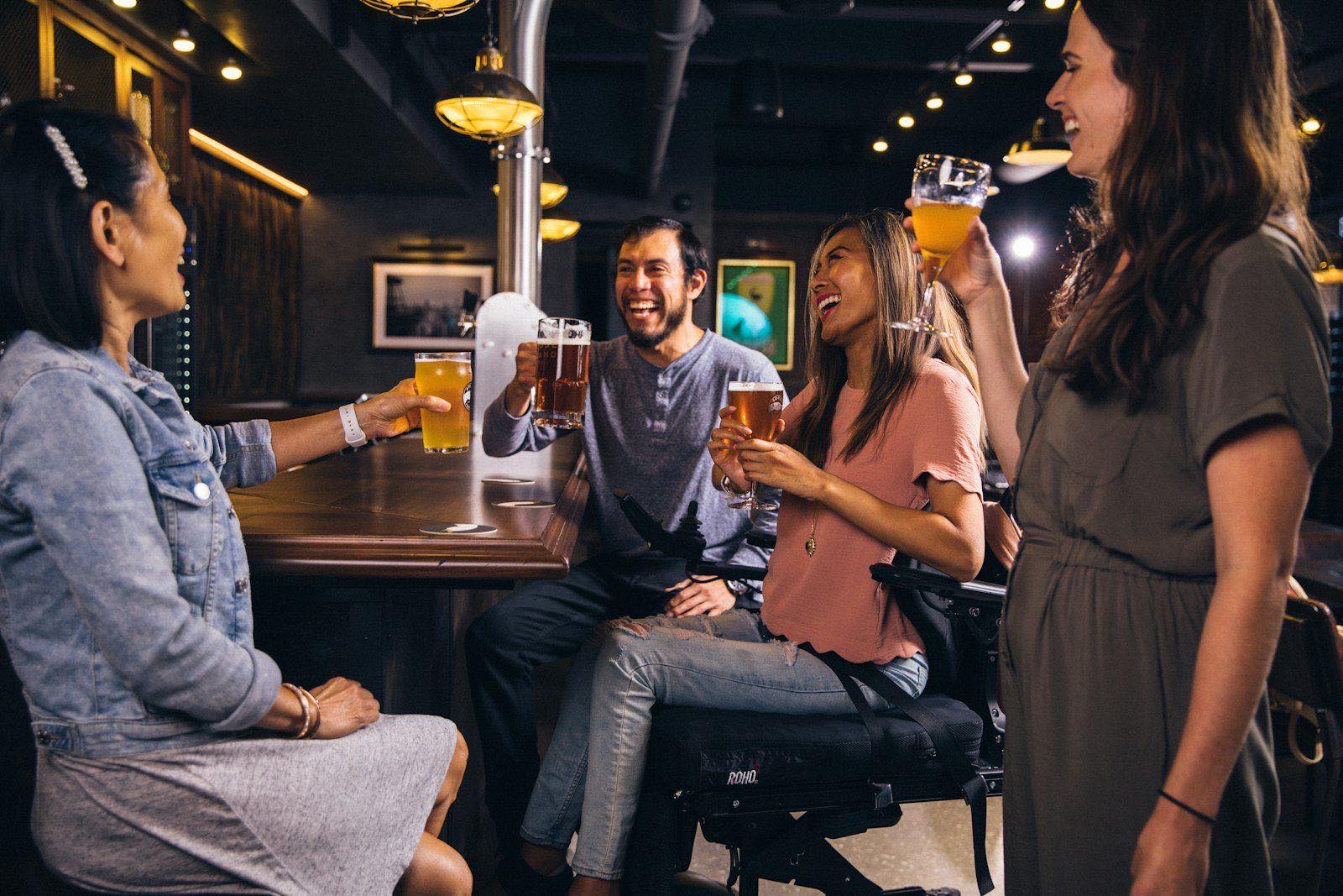 Friends laughing and toasting with drinks at a small bar
