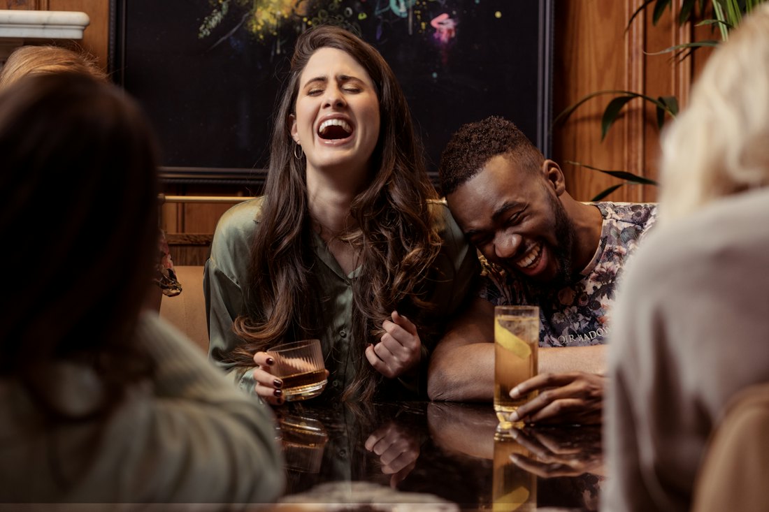 Friends laughing together at a table in a small bar